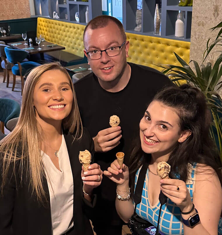 Three people in a bar, smiling while holding ice cream